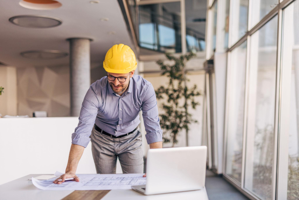 Project engineer in yellow hard hat reviewing blueprints